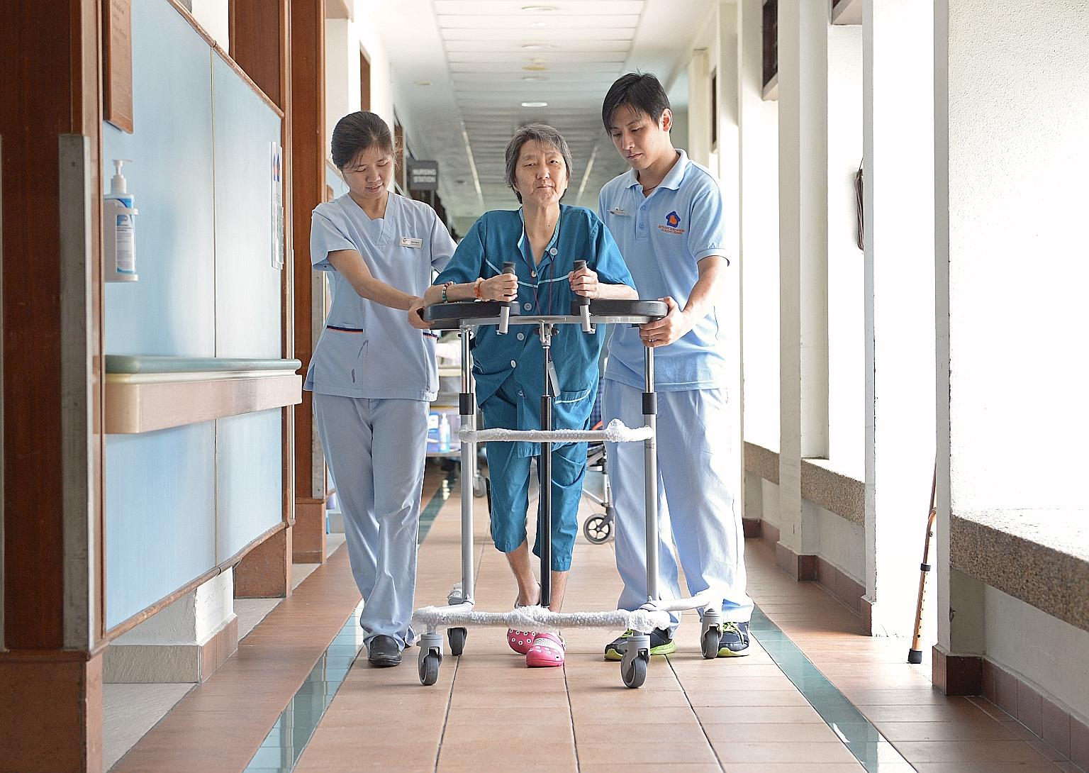 Nurse Myint Myint (left) and physiotherapy associate Tan Lip Yiap (right) attending to a patient at the Bethany Methodist Nursing Home yesterday. The nursing home will receive its first batch of around five staff nurses and physio- therapists in end-