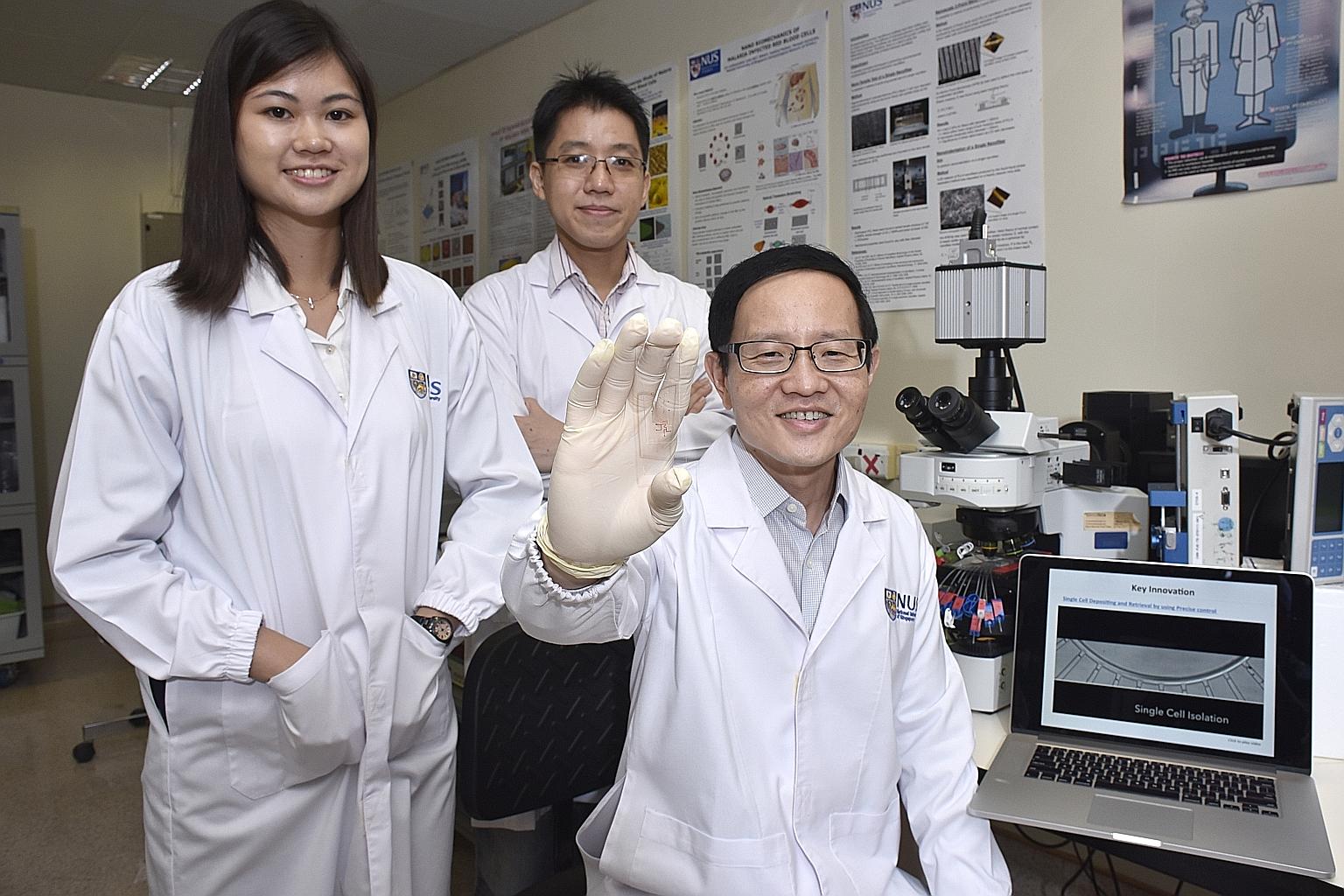 Professor Lim, 50, holding up a microfluidic chip that could pave the way for more personalised medicine when treating cancer patients. Ms Trifanny Yeo Zhi Xiang, 26, and Dr Tan, 35, are also part of the research team that designed the device.