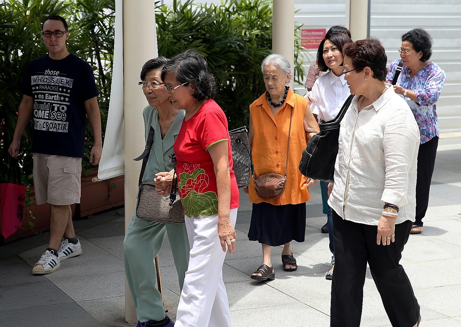 Madam Chung Khin Chun (in orange top) leaving the State Courts with her relative and friends after a hearing earlier this month.