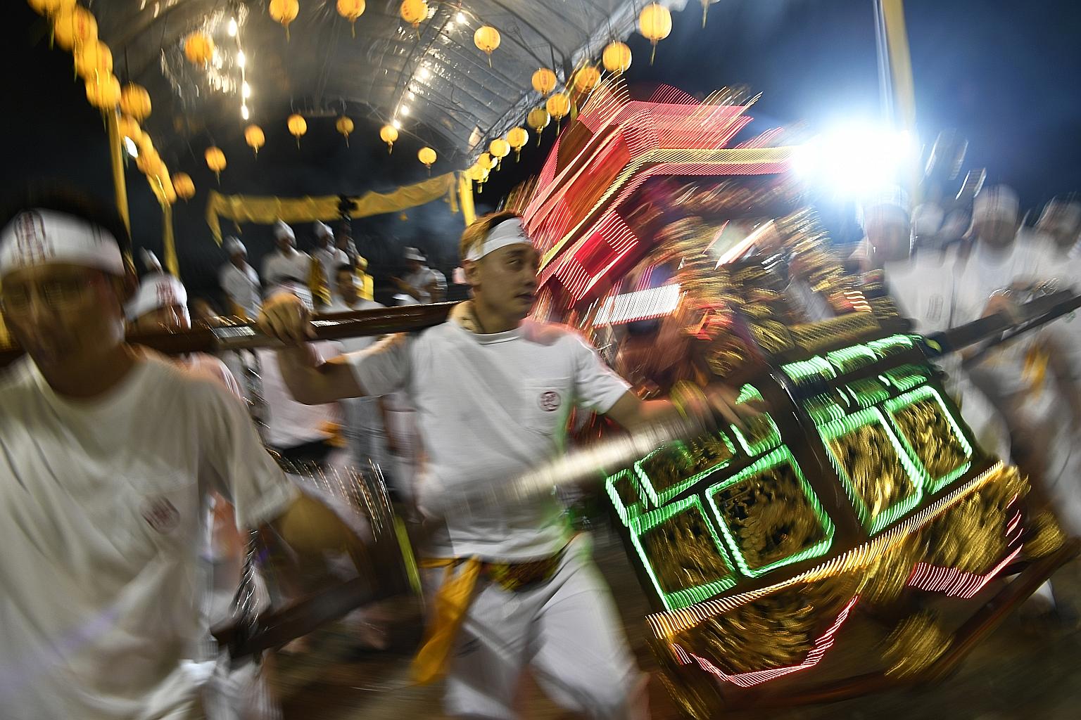 Taoist devotees last night holding a sedan chair as it sways, signifying the arrival of the Nine Emperor Gods.