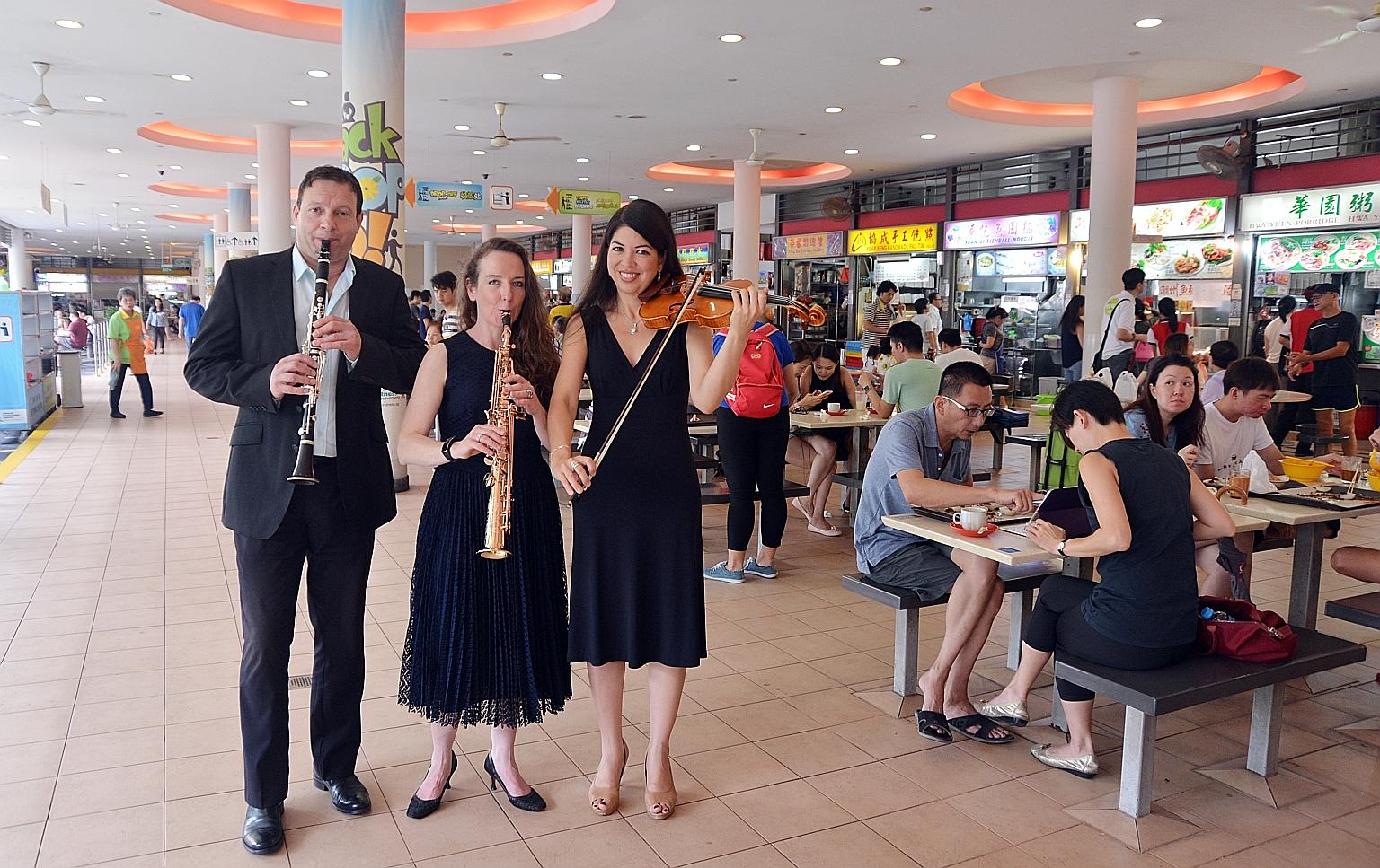 Visitors to Tiong Bahru market yesterday were greeted by an unusual sight - members of the Australian World Orchestra going around taking photographs with curious residents. Among the musicians were (from left) clarinetist Frank Celata, saxophonist C