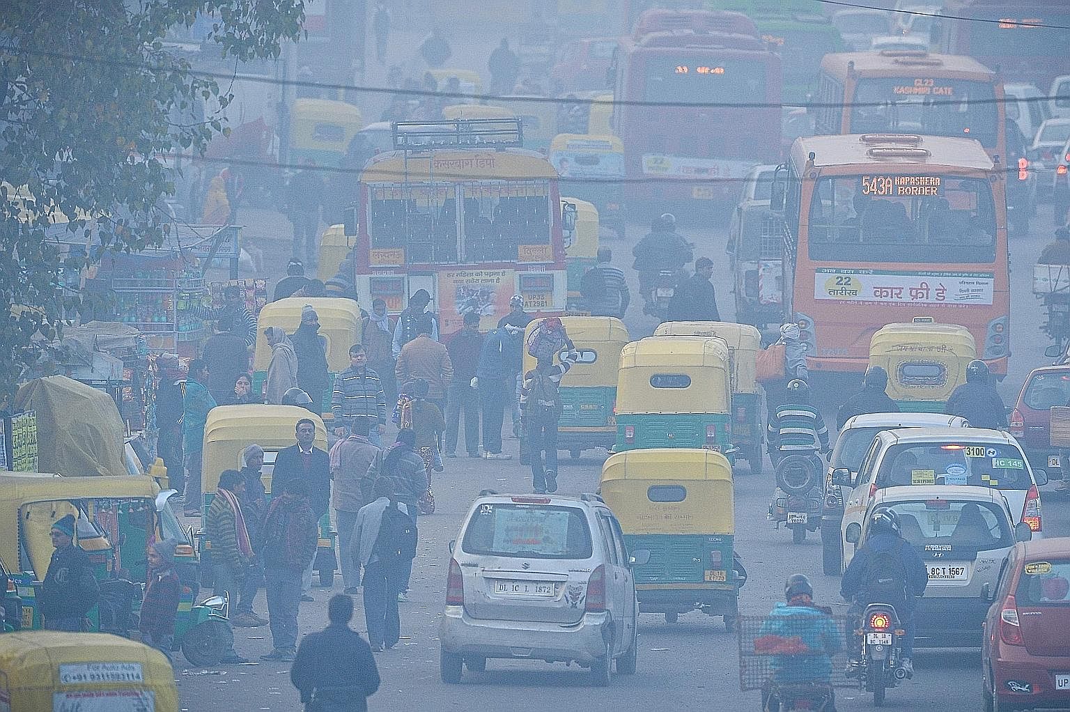 Commuters travelling on a polluted road near a bus terminus in New Delhi.