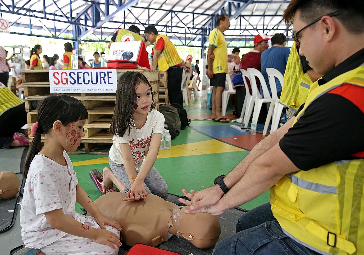 Sisters Quek Gek Ling (left), six, and Gek Boon, eight, learning about CPR from Community Emergency Response Team member Adris Chong at a Hougang block in July. There is greater awareness of the benefits of being trained in CPR, and more schools, com