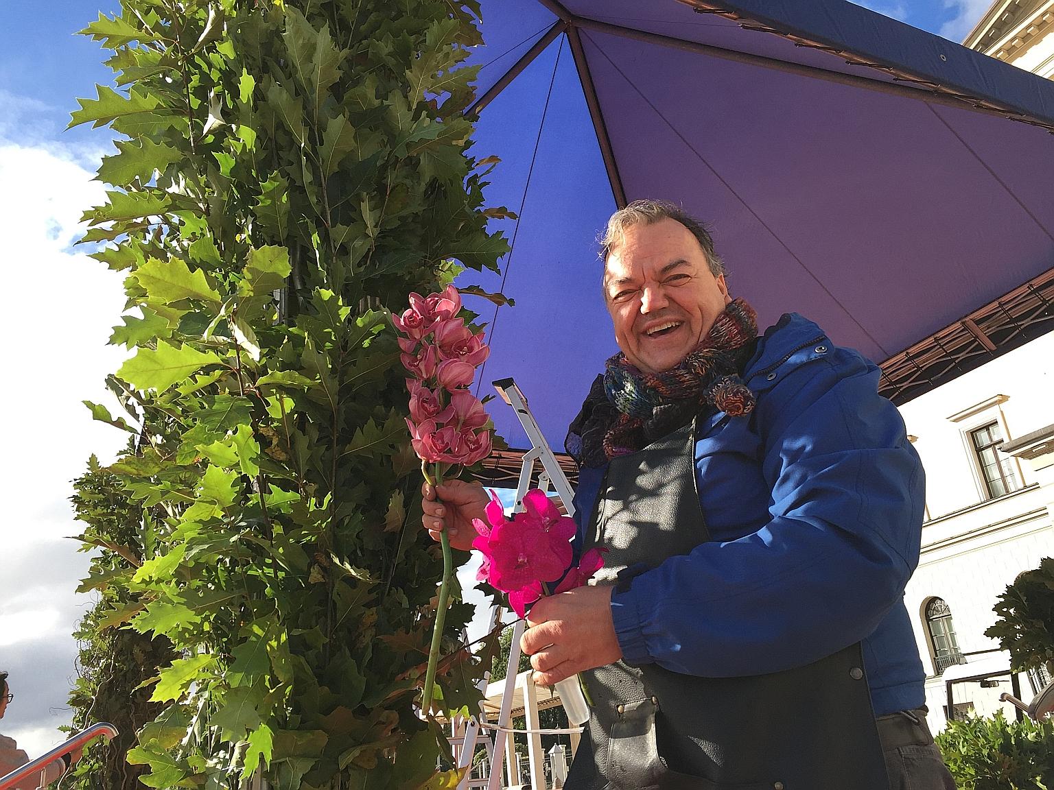 Florist Nils Norman Ivrsen decorating a stage with orchids. The stage is being set up in front of the Royal Palace where King Harald V and Queen Sonja will welcome President Tan.