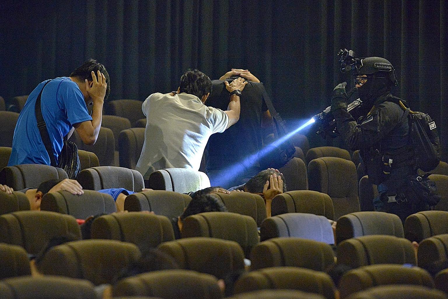 Moviegoers, played by SAF servicemen, being marched out of a cinema hall after Special Operations Task Force officers had taken out five "terrorists" inside, during a media preview of the counter- terrorism exercise that was held yesterday.