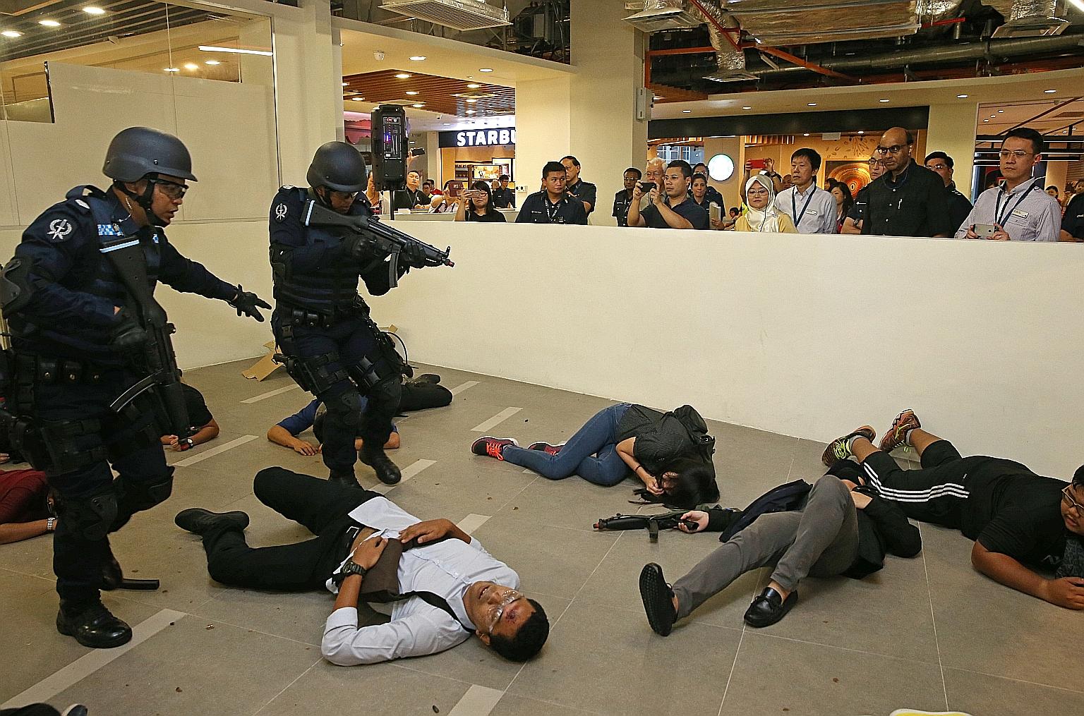 Police Emergency Response Team officers carrying out an anti-terrorism exercise in the food and beverage area of Ng Teng Fong General Hospital yesterday evening as DPM Tharman looks on.