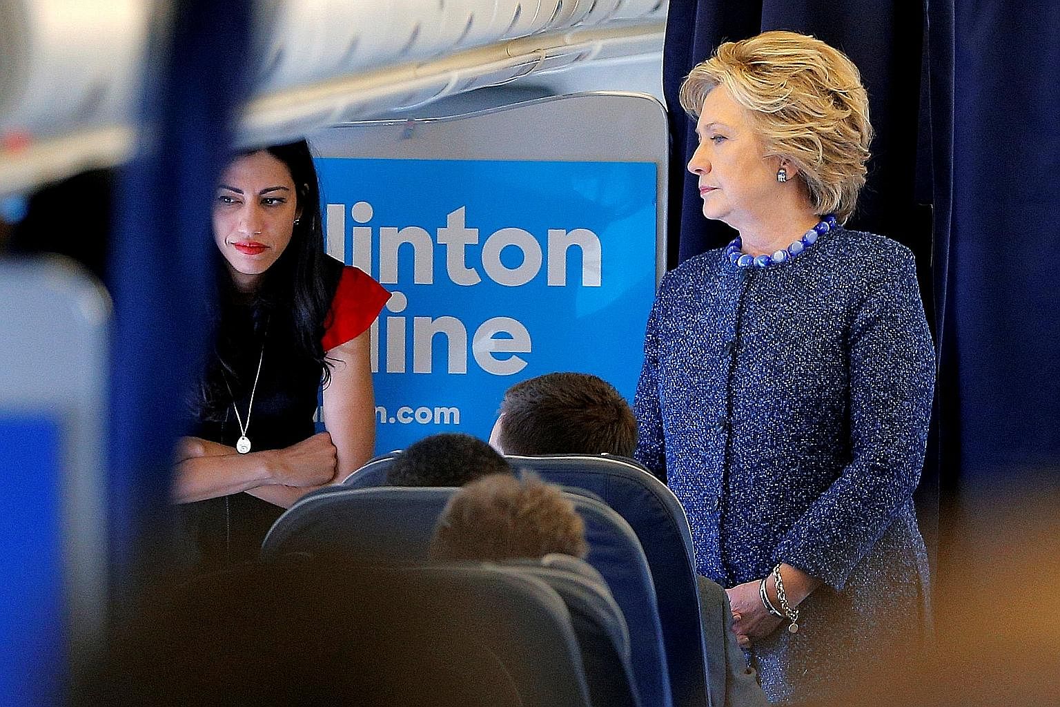 Mrs Clinton with her aide Huma Abedin onboard her campaign plane on Friday. The e-mail that triggered the current scandal surfaced because of investigations into sexual messages allegedly sent to a minor by Ms Abedin's husband, former congressman Ant