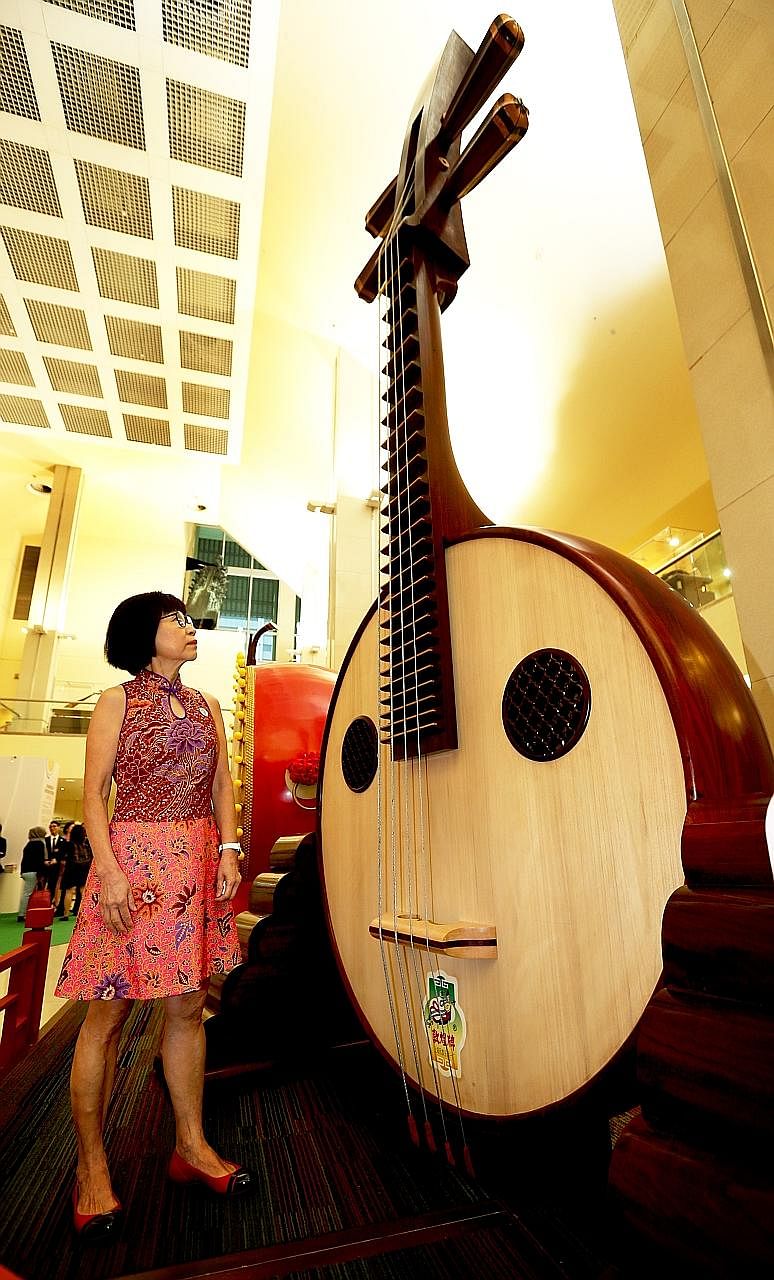 Ms Chek with a 4.6m-tall ruan weighing 702kg at the foyer of the Singapore Conference Hall, where a giant erhu and guzheng are also on display - part of an exhibition marking two decades of the Singapore Chinese Orchestra.