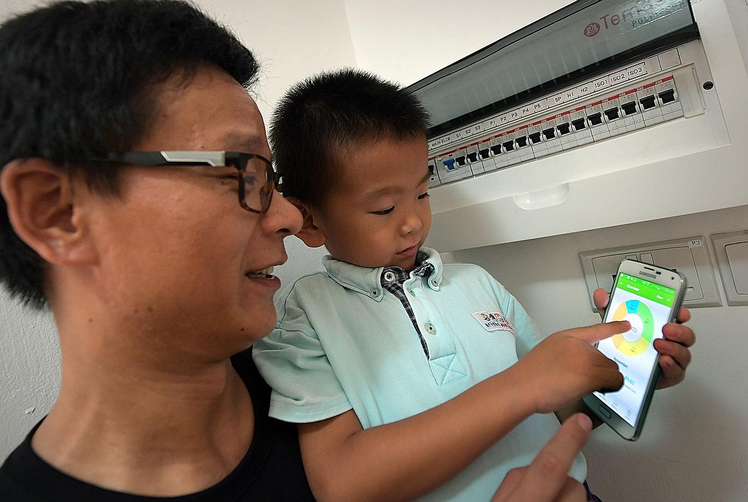 Mr Bai Zemin and his son Zhenxuan with the app that shows electrical consumption in their apartment, where the Temasek Polytechnic system is being tested.
