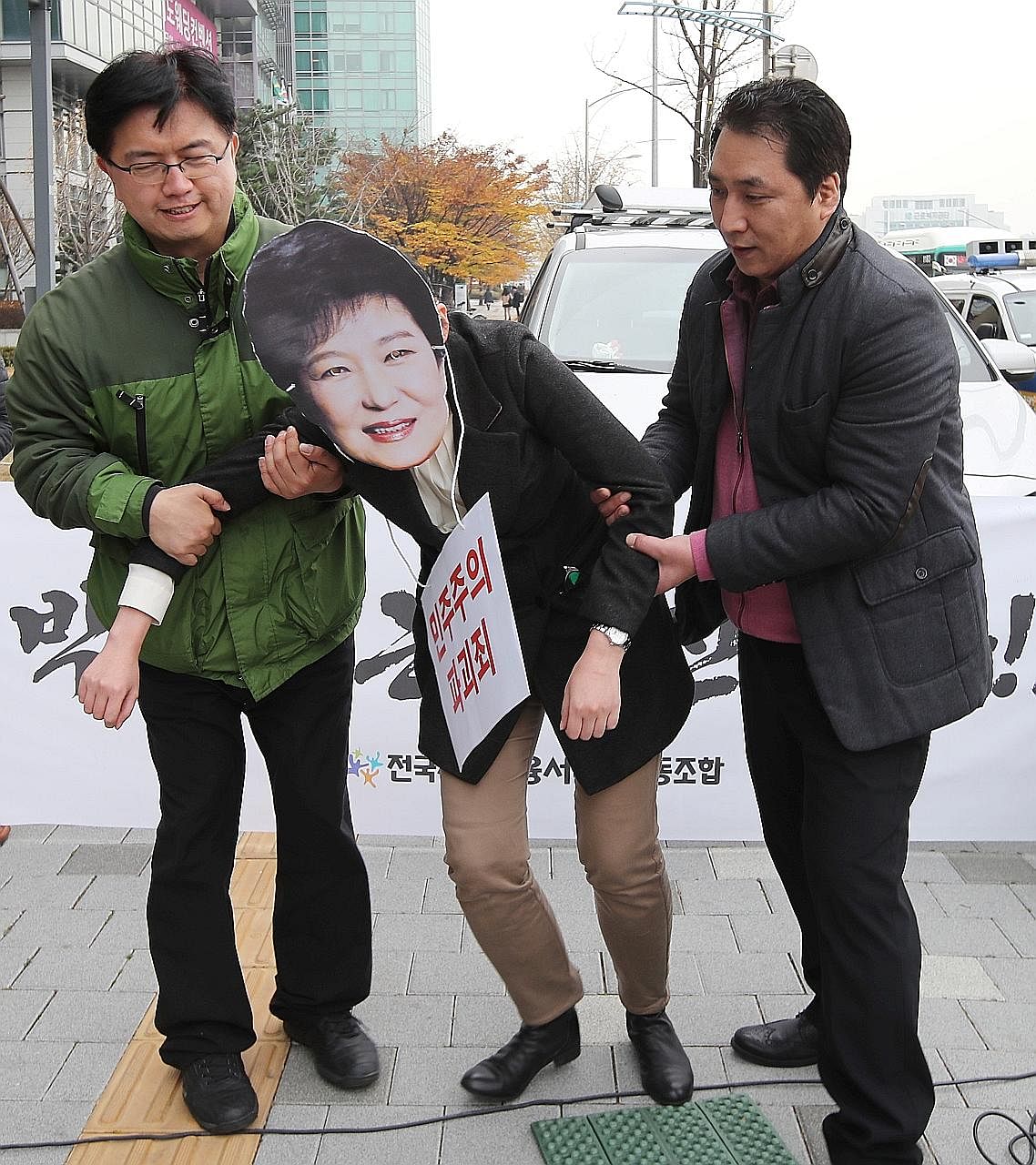 Demonstrators, one of whom is wearing a mask of President Park, taking part in a rally calling for the leader to step down. The snowballing saga is giving both the President and nation a bad name.