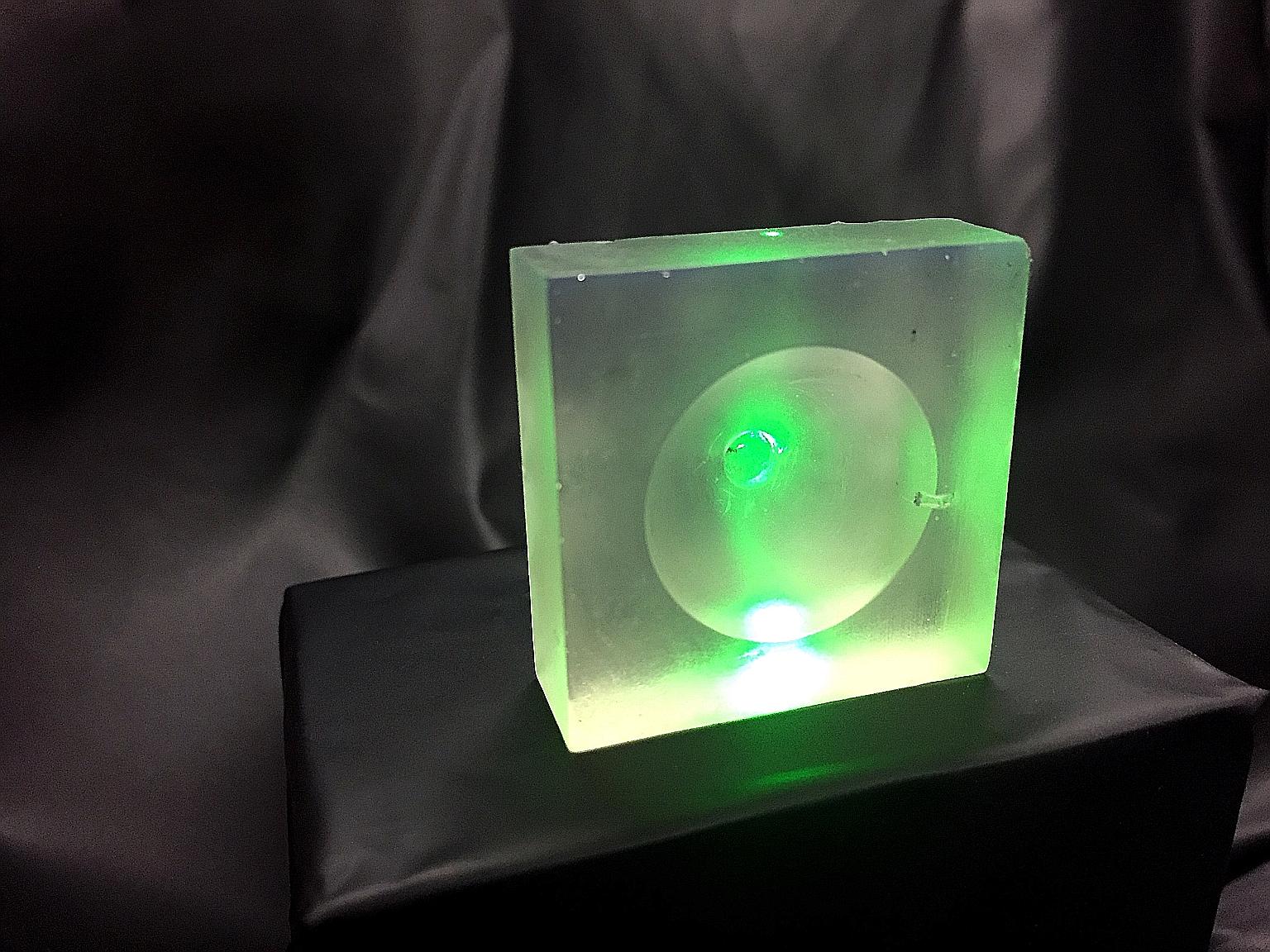 A green laser shoots through one of the new 3D-printed resin lenses that could be used in an ultrasound device.