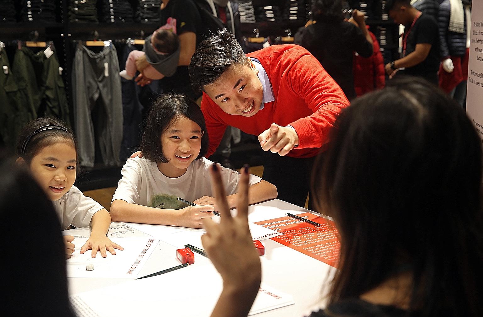 On Saturday, artist Peter Zhuo (in red) - better known as Peter Draw - guided Liu Ruoran (at left), eight, and Lydia Lim, 10, as they sketched portraits of shoppers at the Uniqlo store in Orchard Central mall. The two kids were among 12 The Business 