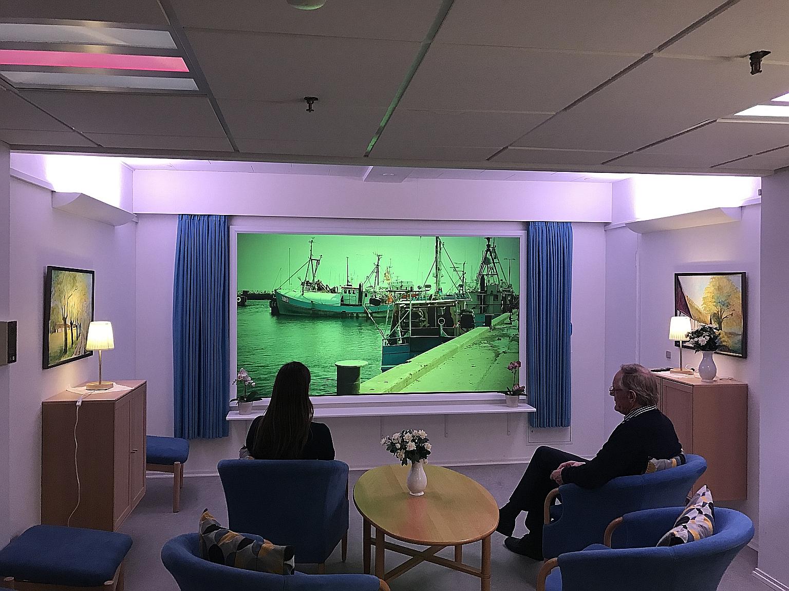 A room for dementia patients at Lindehaven Care Centre in Copenhagen, which uses different lighting to regulate the body's natural circadian rhythm. Images relevant to a patient's past, such as a familiar place, are also shown on a screen as a form o