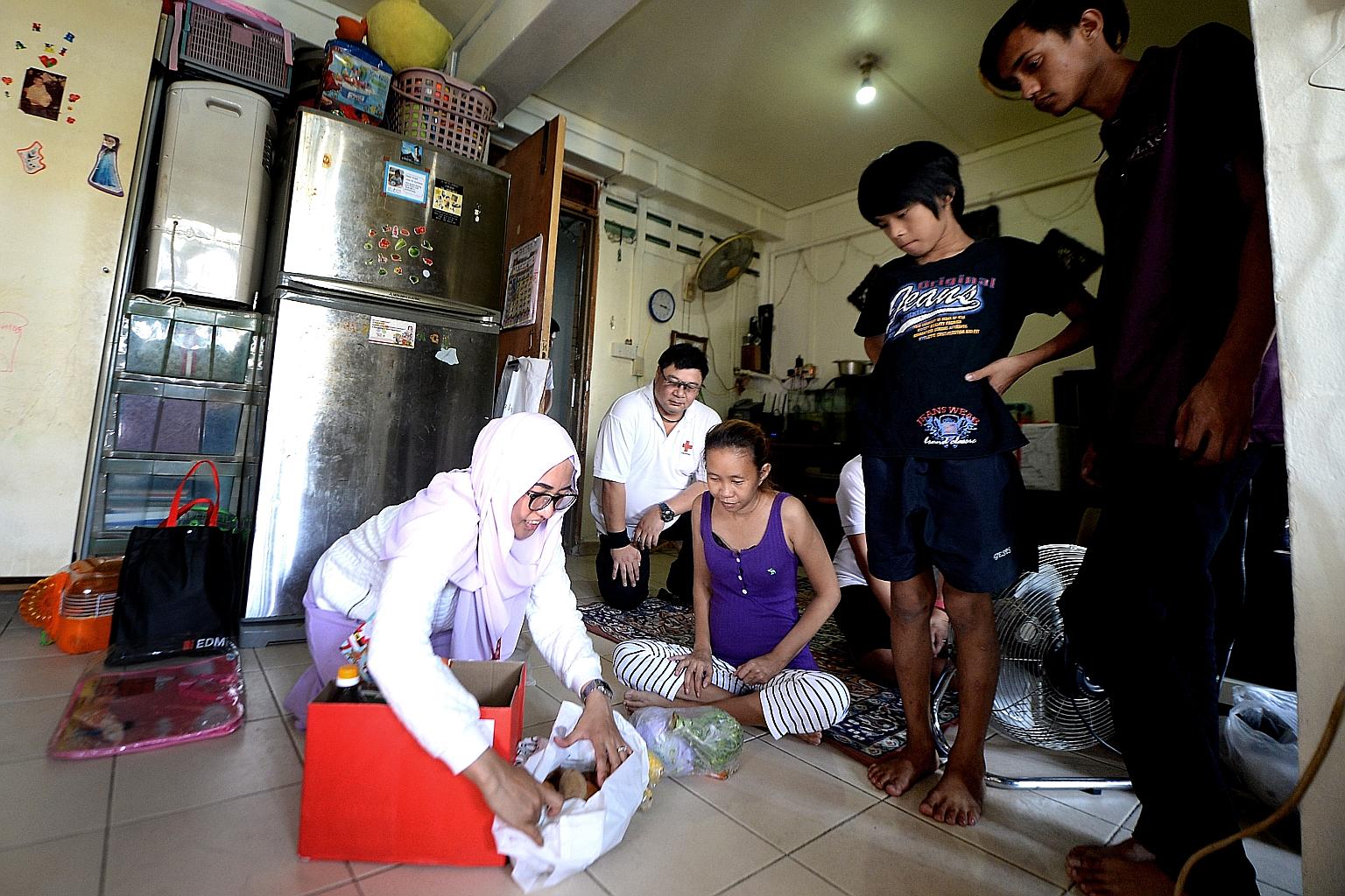 Above: (from left) Red Cross staff Kartini Saat and Mark Tan with Madam Siti Mariam Aman, Aszril Ang and Khairul Baktiar. Right: Boys' Brigade members and some of their family members packing hampers for distribution yesterday.