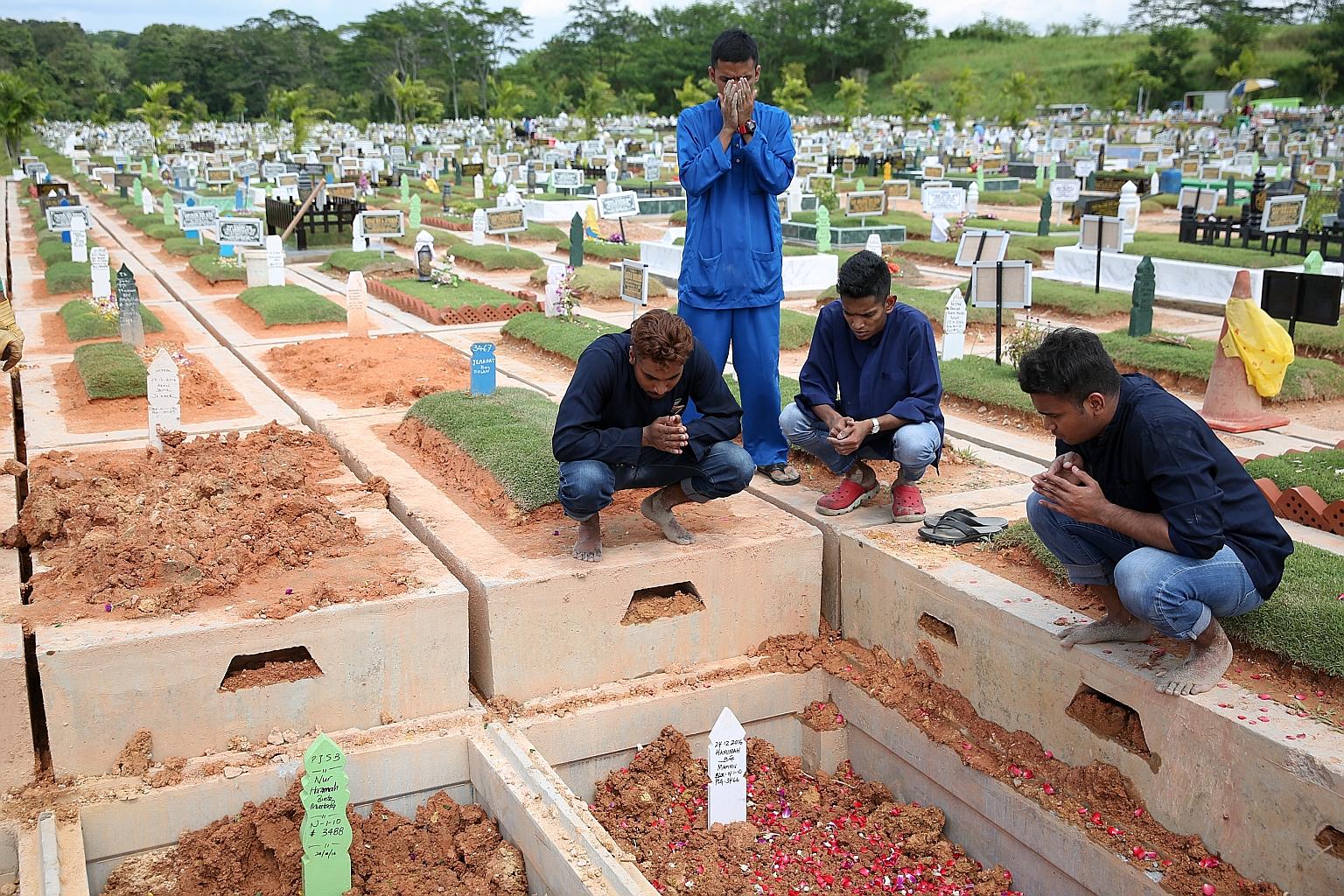 Relatives of Madam Hamimah Mammu, who died in the crash, praying after her burial on Sunday at Choa Chu Kang Muslim Cemetery. The bus driver reportedly had just three hours' rest before he set off that night.