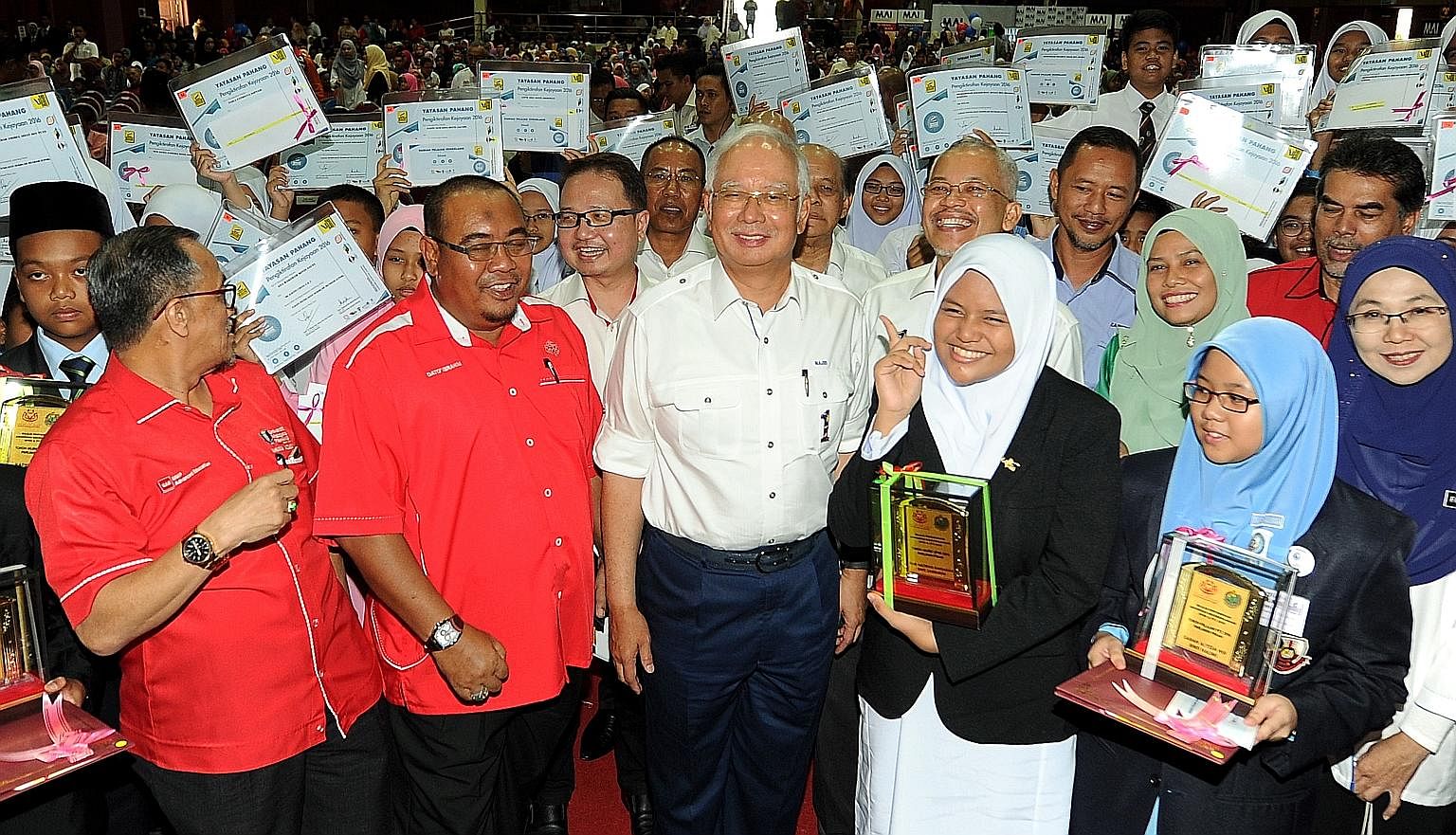 Mr Najib Razak (centre), seen here at an event in Pahang yesterday, criticised his predecessor Mahathir Mohamad for saying the opposition would continue giving cash handouts after criticising the aid programme earlier.