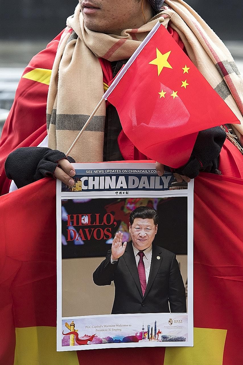 With a Chinese flag and the China Daily in hand, a supporter waits outside the Parliament building in Bern for Mr Xi. The Chinese leader will deliver a keynote speech in Davos today.
