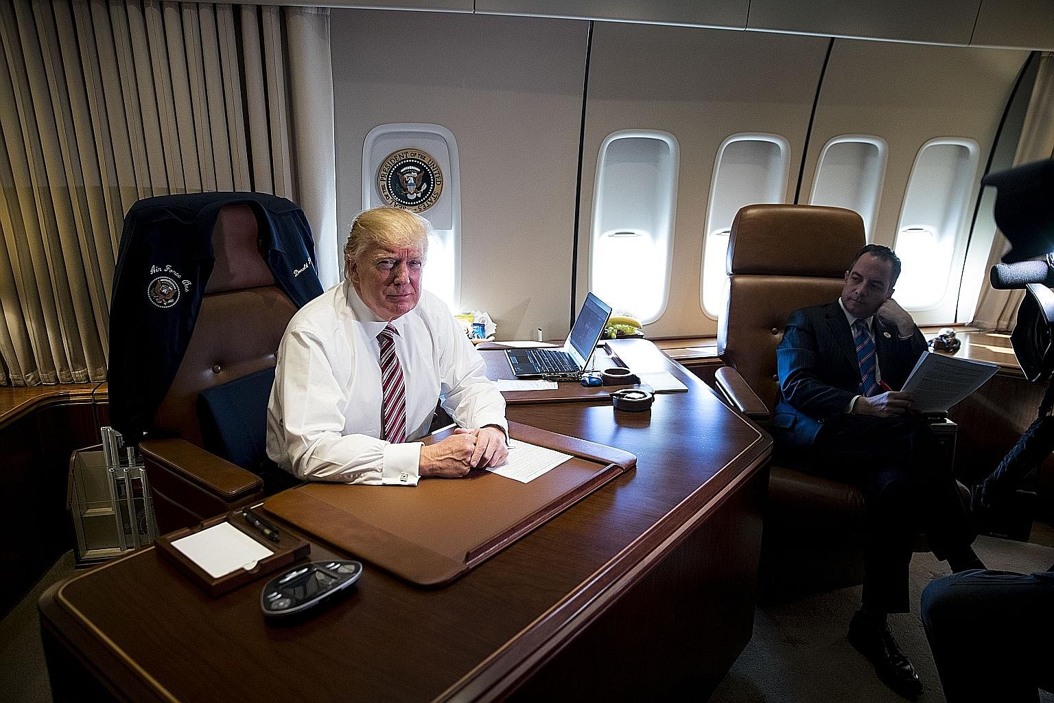 Mr Trump on board Air Force One with chief of staff Reince Priebus during a trip to Philadelphia on Sunday. The many executive orders he has issued in his first week as President include pulling out of the Trans-Pacific Partnership trade deal, and gr