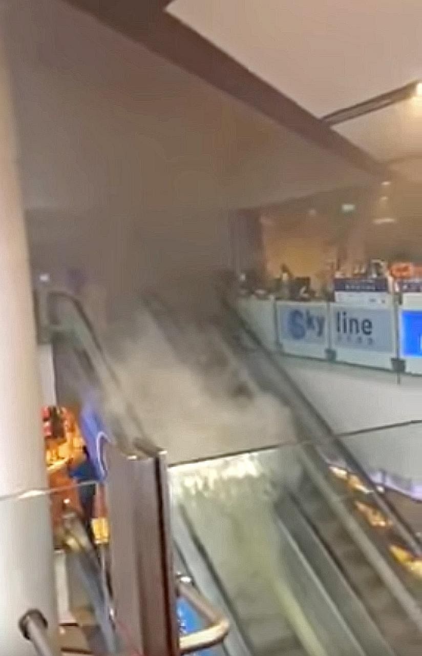 Above: An unidentified person tried to use a fire extinguisher to put out the fire at the Chinatown Point escalator yesterday. An SCDF spokesman said the fire involved electrical wiring at the third-storey escalator landing, and there were no reporte