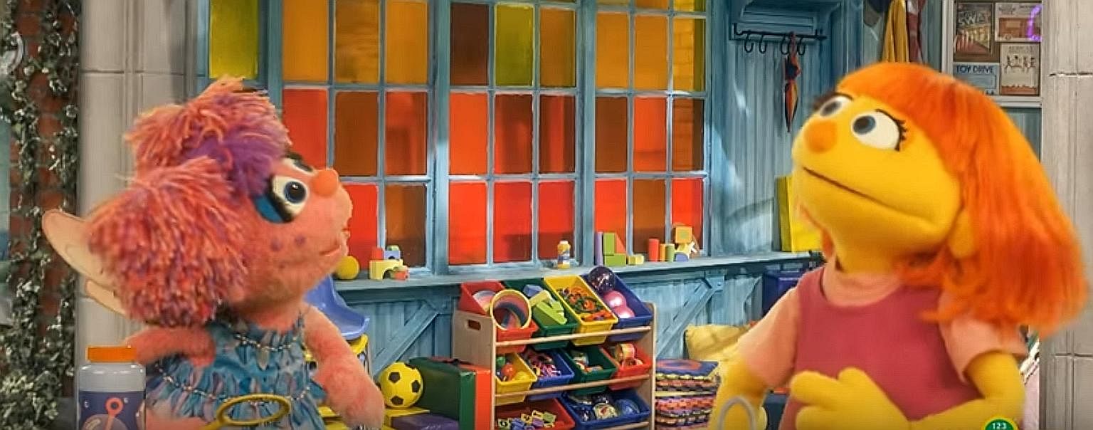 Muppet Abby Cadabby (far left) welcomes orange-haired Julia to Sesame Street.