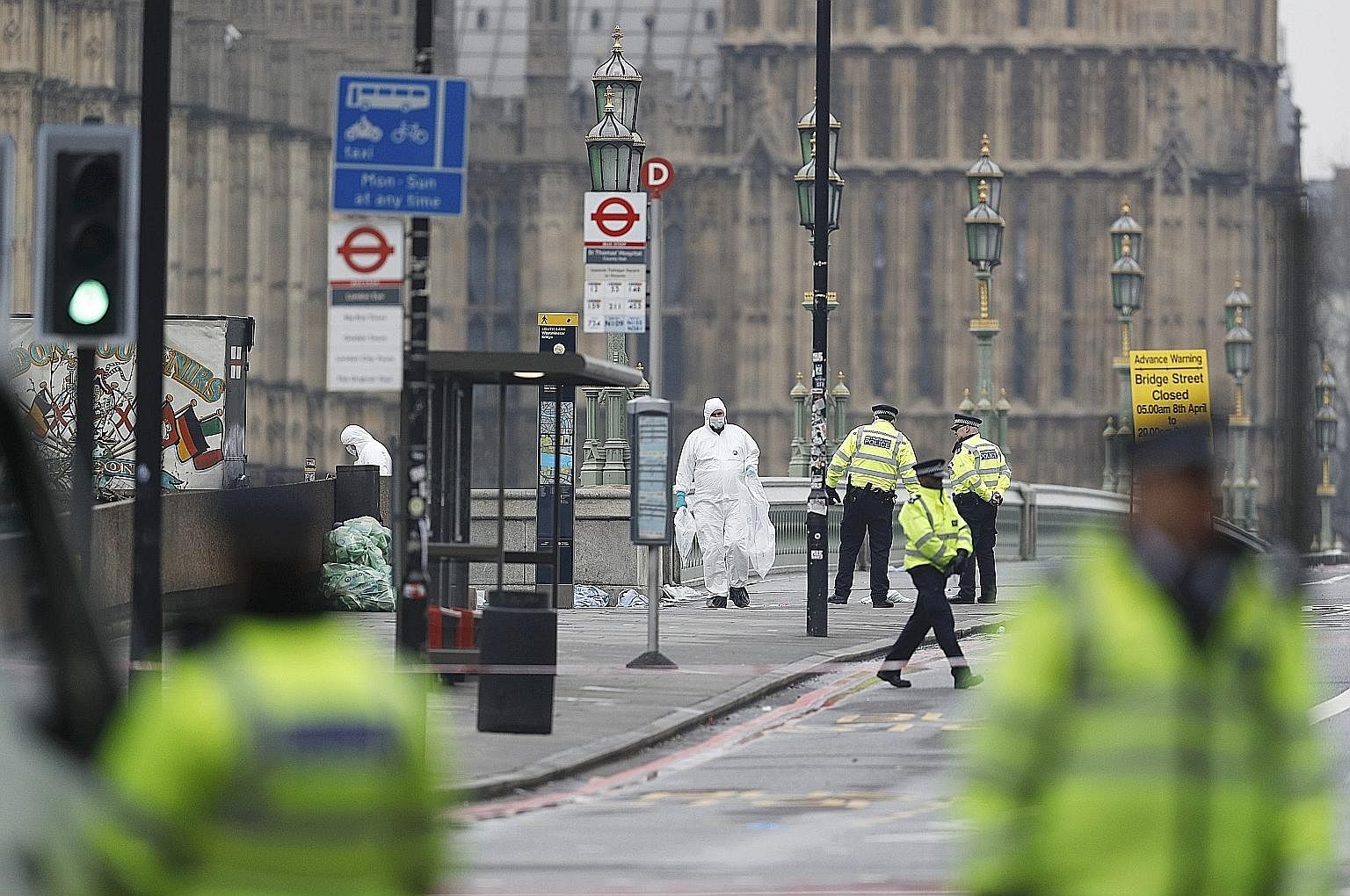 Police officers and forensics investigators working on Westminster Bridge yesterday after an attack by a man driving a car and wielding a knife left four people dead. A police officer entering a building in Birmingham, one of the properties raided af