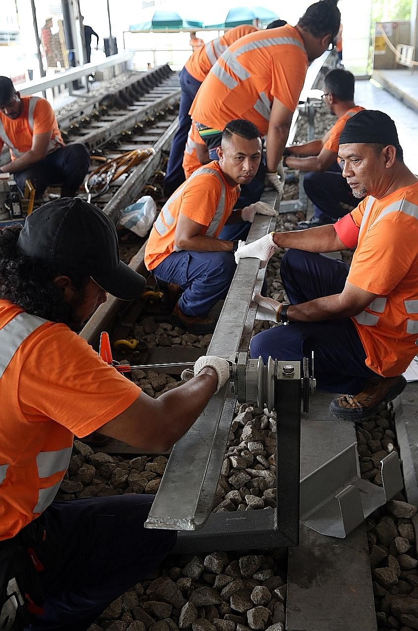 SMRT workers demonstrating the replacement of a high-speed ramp at Bishan Depot yesterday. While the NSL's reliability has risen by 15 per cent, the EWL's was unchanged for the 12-month period ending March 31.