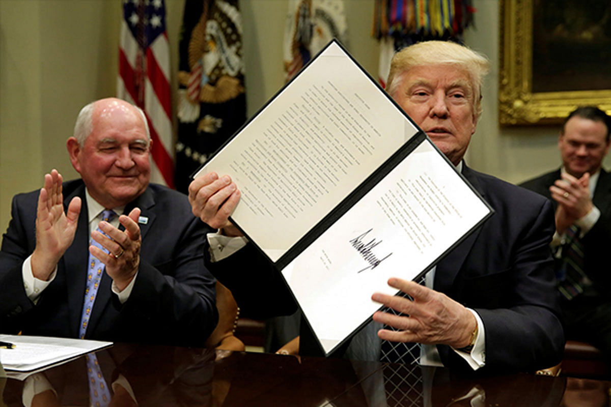 US President Donald Trump shows a signed executive order next to Secretary of Agriculture Sonny Perdue during a roundtable discussion with farmers at the White House.