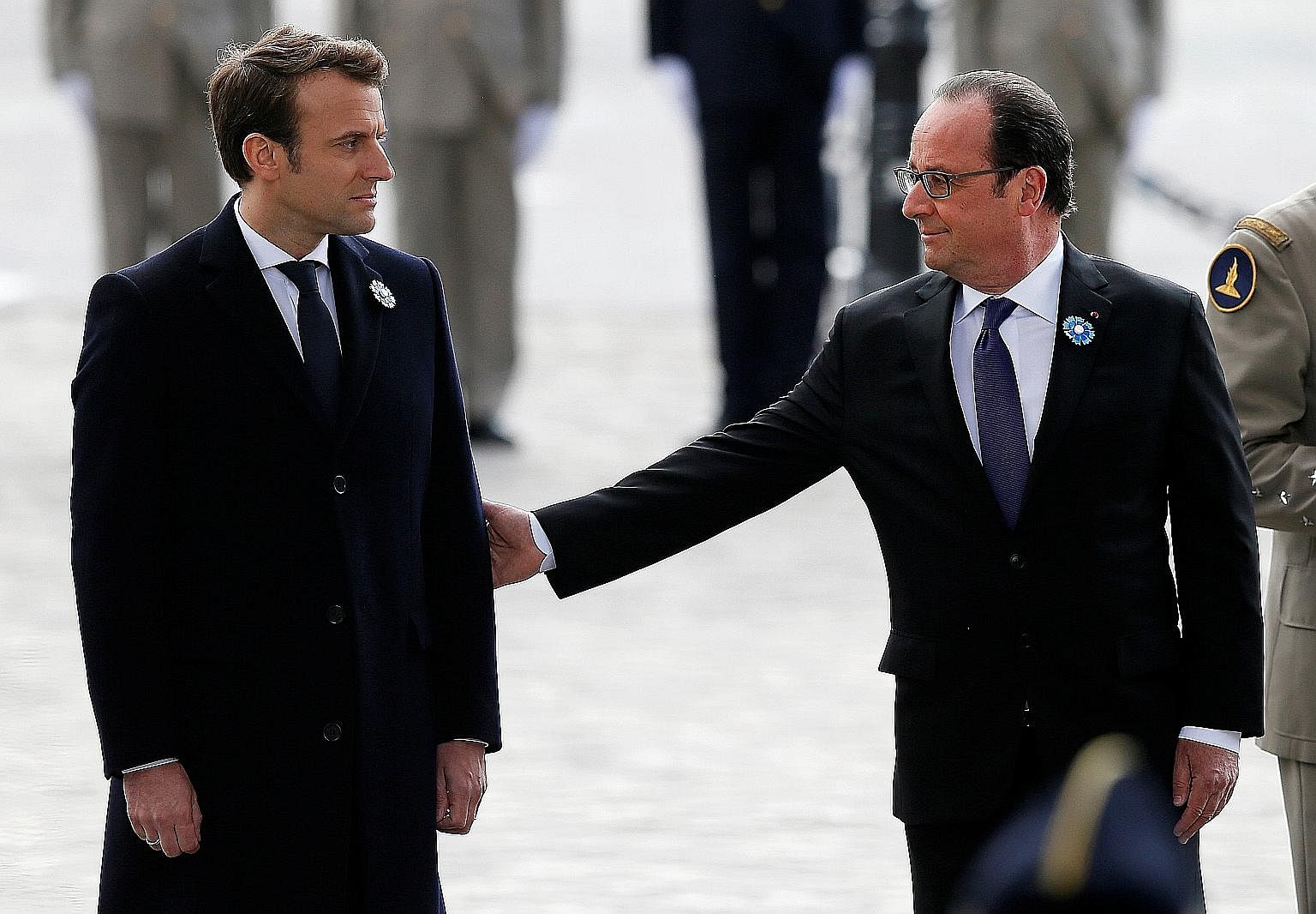 Outgoing French President Francois Hollande (right) reaching out to President-elect Emmanuel Macron as they attended a ceremony to mark the end of World War II at the Tomb of the Unknown Soldier at the Arc de Triomphe in Paris yesterday. Above: Frenc