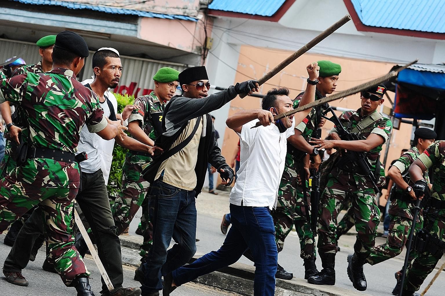 Indonesian hardline Muslim activists being restrained by military personnel as they shouted slogans during a local tribal festival in Pontianak, West Kalimantan province, on May 20. The divisive gubernatorial Jakarta election has brought up the quest