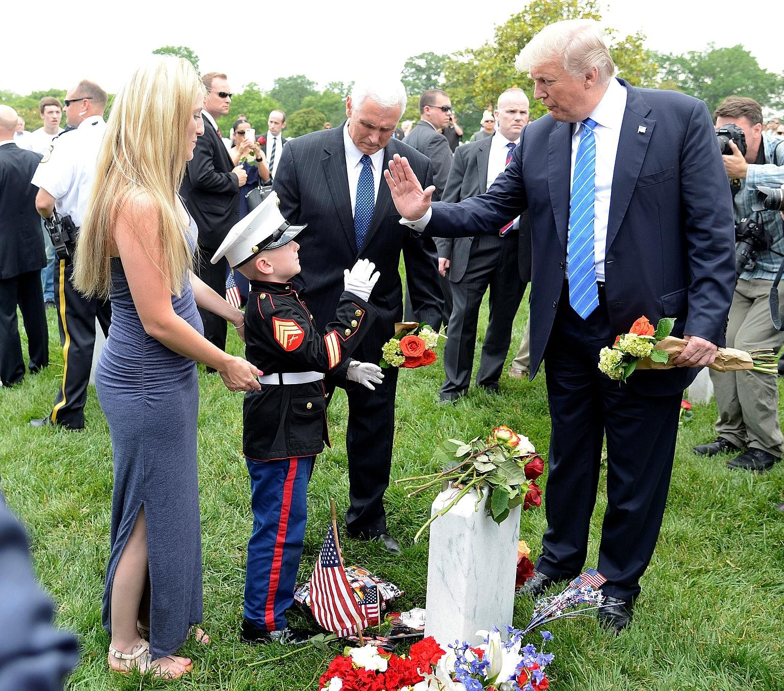 Mr Donald Trump exchanging high fives with the son of a US marine who was killed in training, as the boy's mother looks on, at Arlington National Cemetery in Virginia, which the US President visited on Monday to mark Memorial Day.