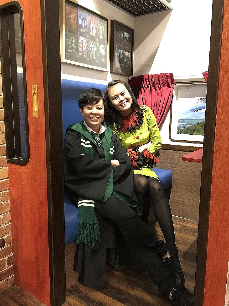 Ms Chin Xuan (far left), in a Slytherin school uniform, and Ms Jo Chua, wearing a Rita Skeeter outfit she made herself. The ardent Harry Potter fans are sitting in a Hogwarts Express train carriage at the Singapore Philatelic Museum’s Harry Potter exhibit
