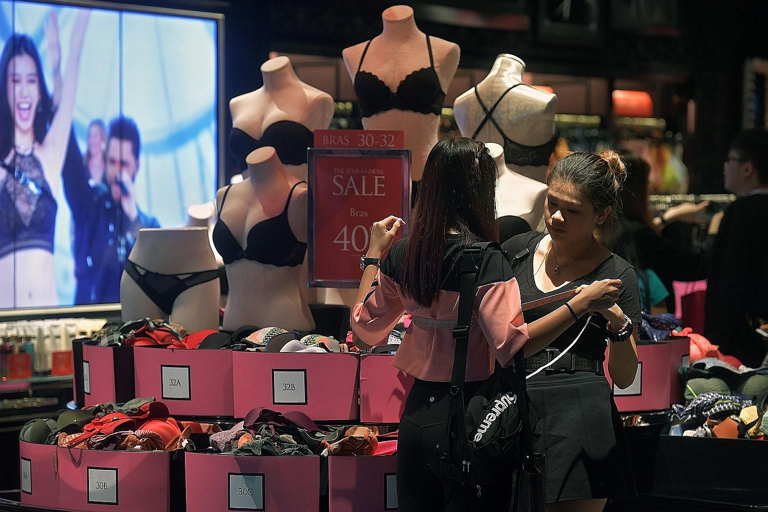 A shopper resting her tired feet at the men's shoe section at Robinsons The Heeren in Orchard Road. A store assistant helping a customer take her measurements during a fitting at the Victoria's Secret store at Mandarin Gallery in Orchard Road. The st