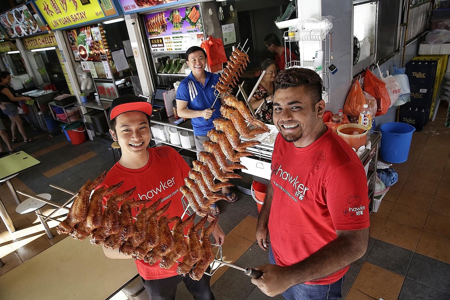 Yihawker founder Jonathan Tan (far left), 27, and co-founder Muhd Nur Azhar Mohd Maideen, 25, with Mr Larry Ng (centre), 33, who runs Sin Bedok North BBQ Chicken Wing. 