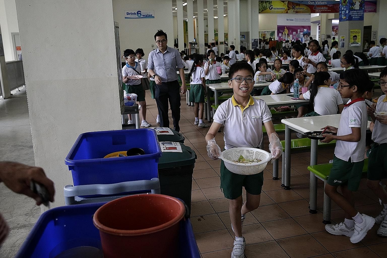 Eleven-year-old Ray Yap, a Primary 5 pupil of Greendale Primary School and a member of its environmental science club, carrying segregated food waste to a food-waste digester on Tuesday. The school started a food-waste reduction programme last month.