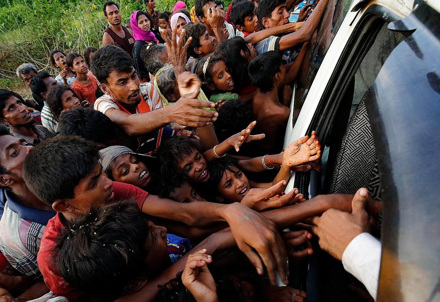 Rohingya refugees reaching for food being distributed near Balukhali in Cox's Bazar, Bangladesh, on Monday. The weight of the majority in mostly Buddhist Myanmar is against the Muslim Rohingya, says the writer, and the popular call is for the army to