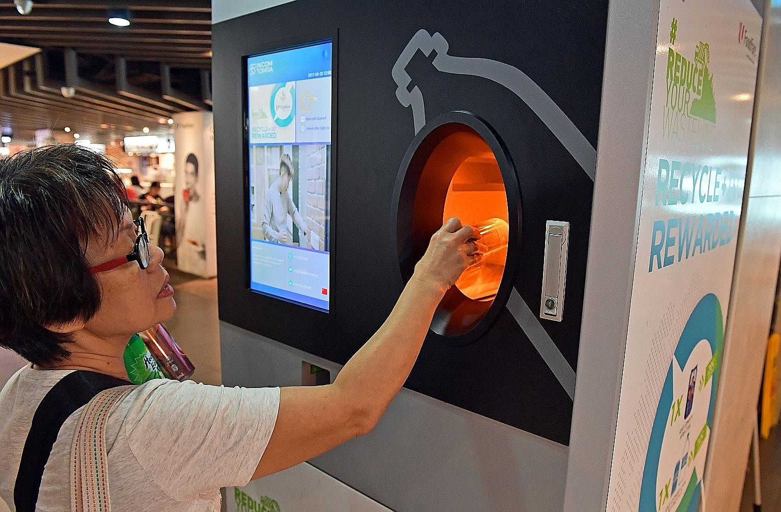 Madam Lau Hong Eng, 63, recycling drink cans at the reverse vending machine at Foodfare@Admiralty, which gives out money or coupons in exchange for an empty can or plastic bottle. Distributor Incon Green Singapore has plans to install 500 machines ac