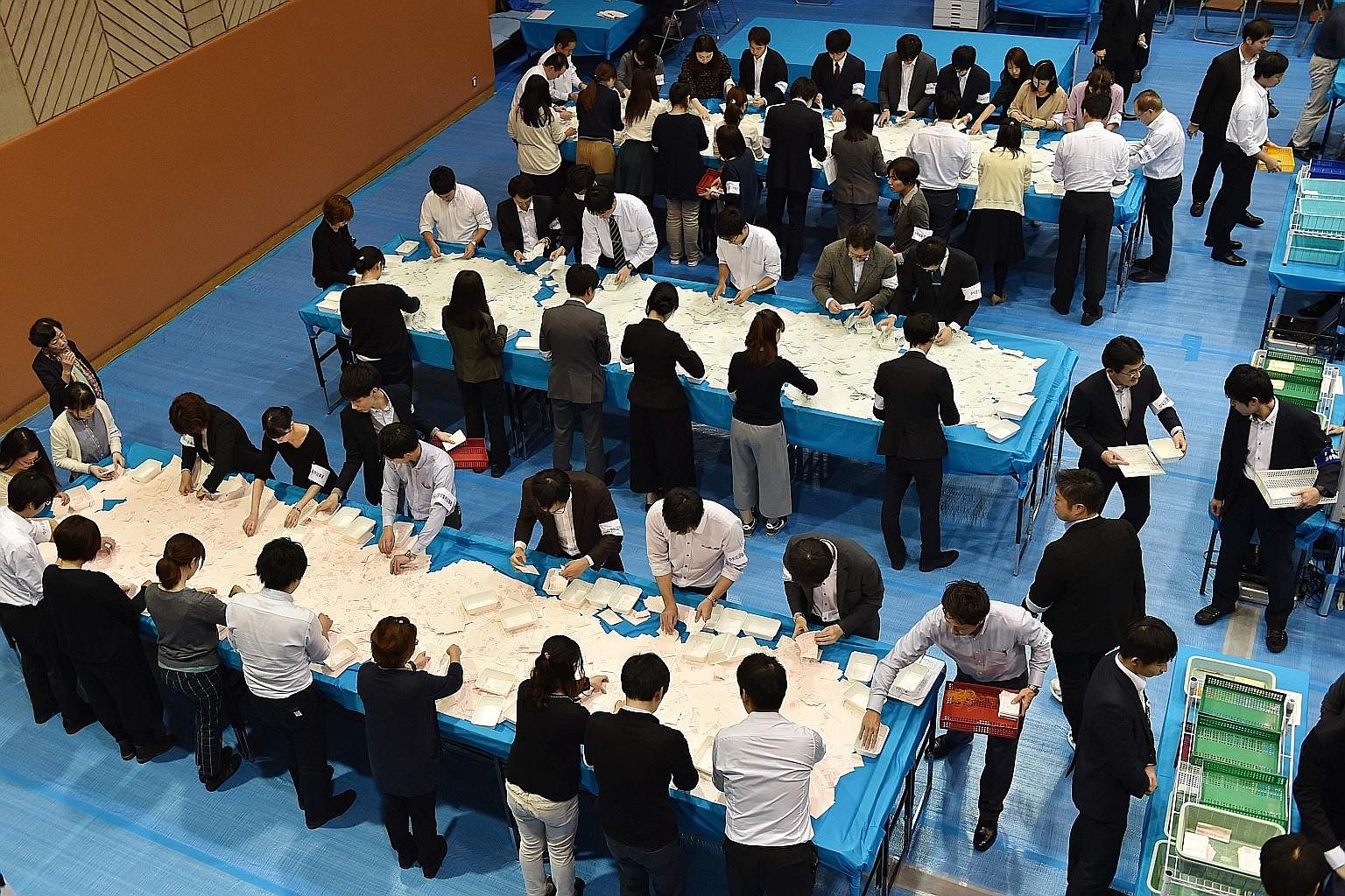 Officials counting ballot papers at an election office in Tokyo yesterday. The LDP-led coalition has secured a two-thirds "super majority" in the powerful Lower House of Parliament.