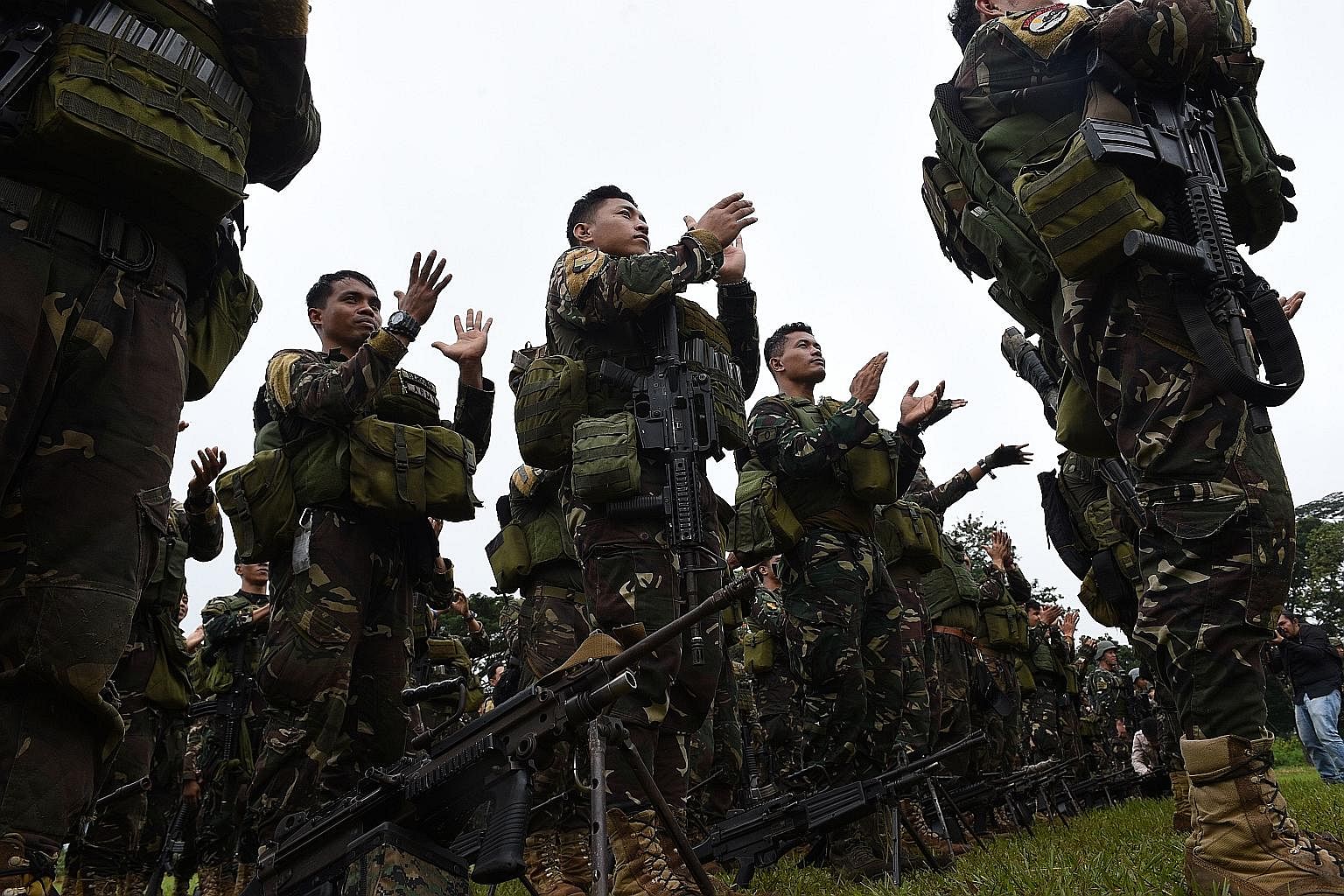 Philippine soldiers who fought against ISIS-affiliated militants applaud during their send-off ceremony inside a military camp in Marawi on the southern island of Mindanao yesterday. While the months-long siege of Marawi has effectively ended, the wa