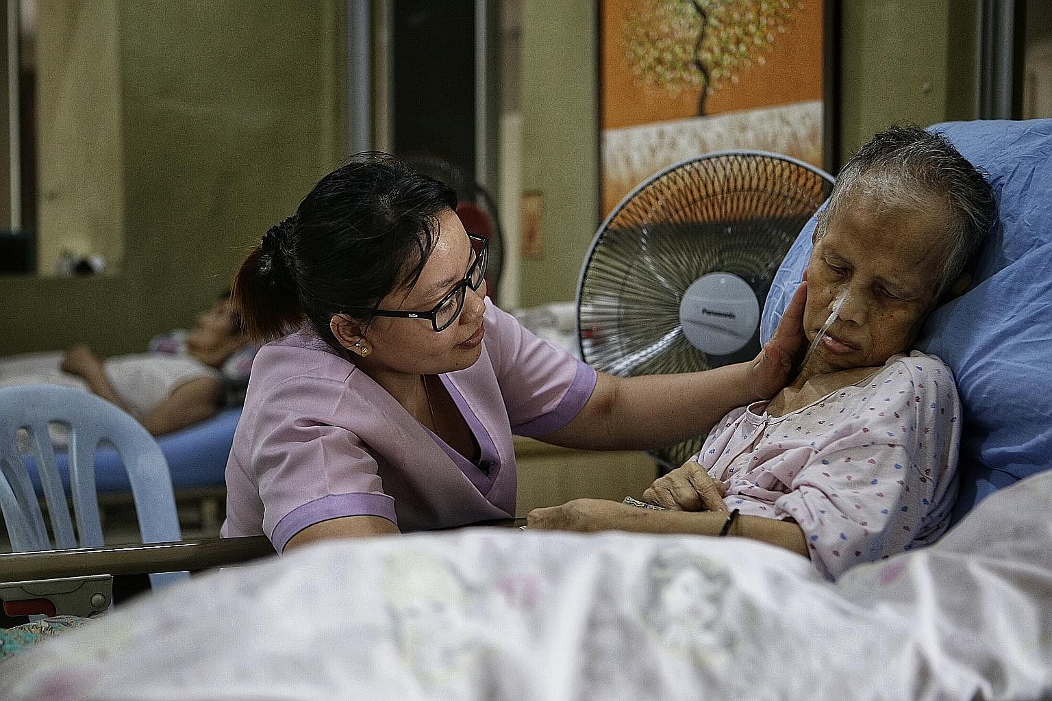 Senior nurse Liew Seenah, 30, consoling 69-year-old Madam Pungut Jumadi at Green Acres Nursing Home (below) in Johor Baru, about 20 minutes' drive from the Causeway. The owner of the home, Mr Yeo Kok Leong, is hoping to find Madam Pungut's family in 