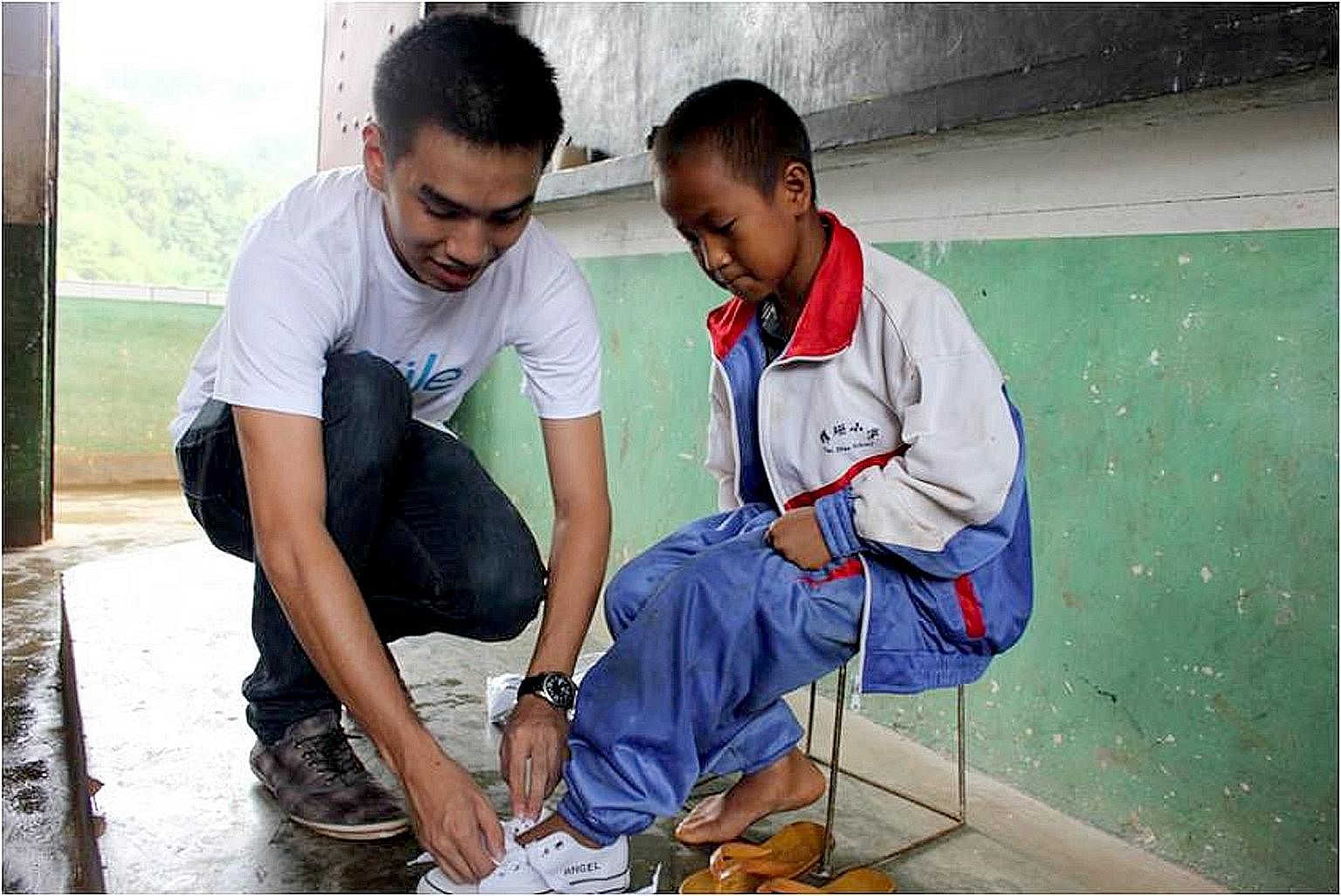 Mr Lee putting on shoes for a schoolboy in Lincang, Yunnan, in 2010. Soule's first batch of flip-flops sold out, and the proceeds were enough to buy 317 pairs of shoes for one entire school in Lincang. Mr Justine Lee was a rebellious child who did ba