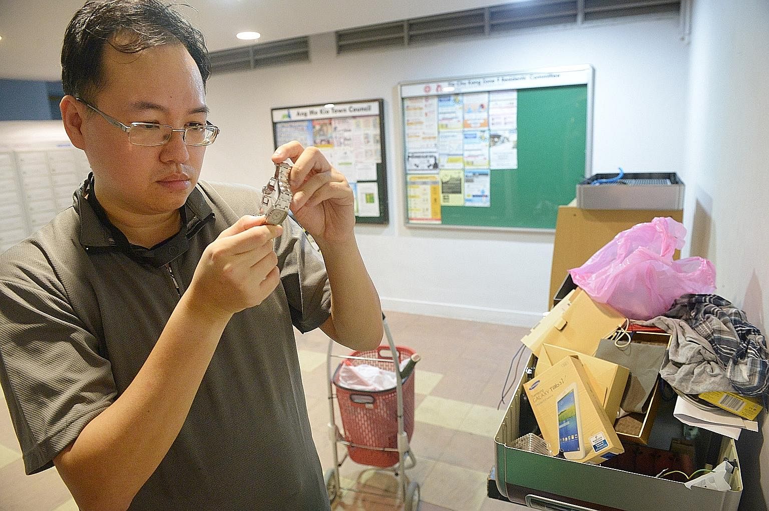 Mr Daniel Tay examining a watch that he found discarded at the void deck of a Housing Board block near his flat in Ang Mo Kio. He says it does not make any sense that people here waste tonnes of food every year when there are others who do not have e