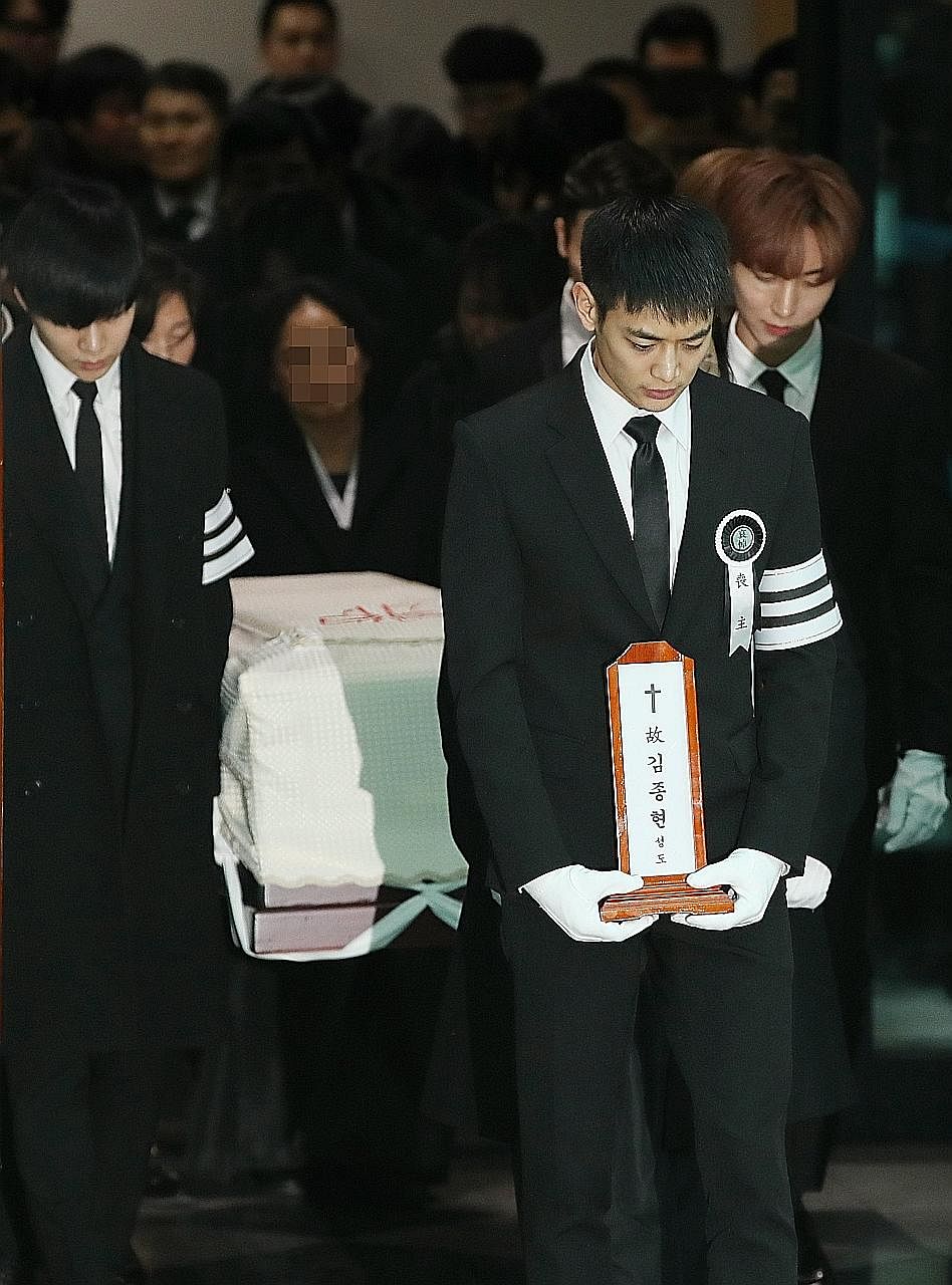 Kim Jong Hyun's SHINee bandmate Minho bearing a plaque topped with a cross and reading "Kim Jong Hyun, believer". Fans of Kim, the lead singer of top South Korean boyband SHINee, weep as a hearse carrying his coffin passes by. Kim's sister, tears cou