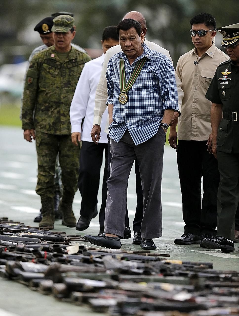 Philippine President Rodrigo Duterte looking at arms confiscated from extremists who had seized large parts of Marawi.