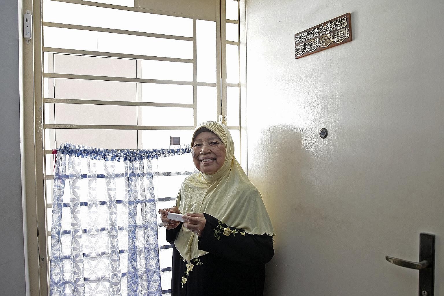 Madam Sitee Marnoor with a door sensor. A similar one was mounted on the frame of her main door in September. Since then, it has sent out three alerts.
