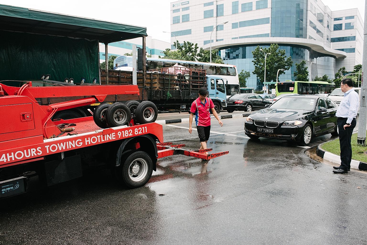 Mr Ricky Ng (right) waiting for his BMW car to be towed after he was caught in Monday's flood near the junction of Upper Changi Road and Bedok North Avenue 4. "The damage is quite bad as water got into the engine, exhaust and air intake system," he s