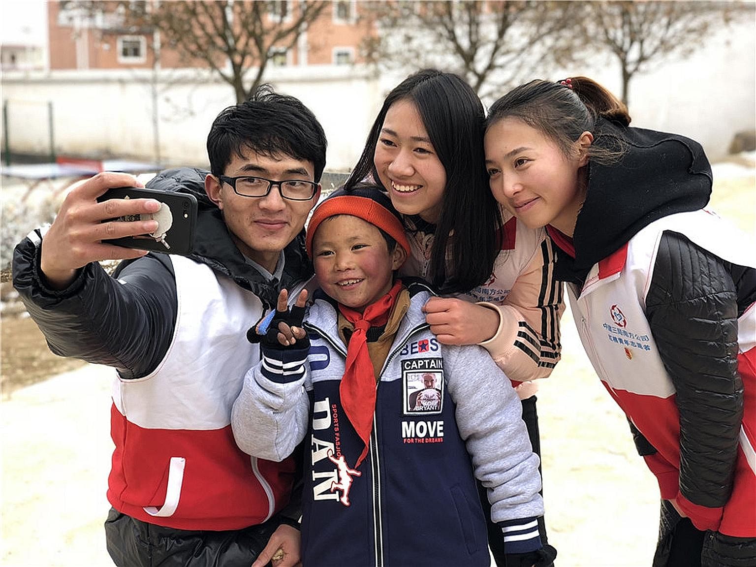 Volunteers with eight-year-old Wang Fuman after helping him put on a pair of gloves. Donations, including winter clothing and heaters for his school in Yunnan, have poured in since his "Snowflake Boy" photo went viral.