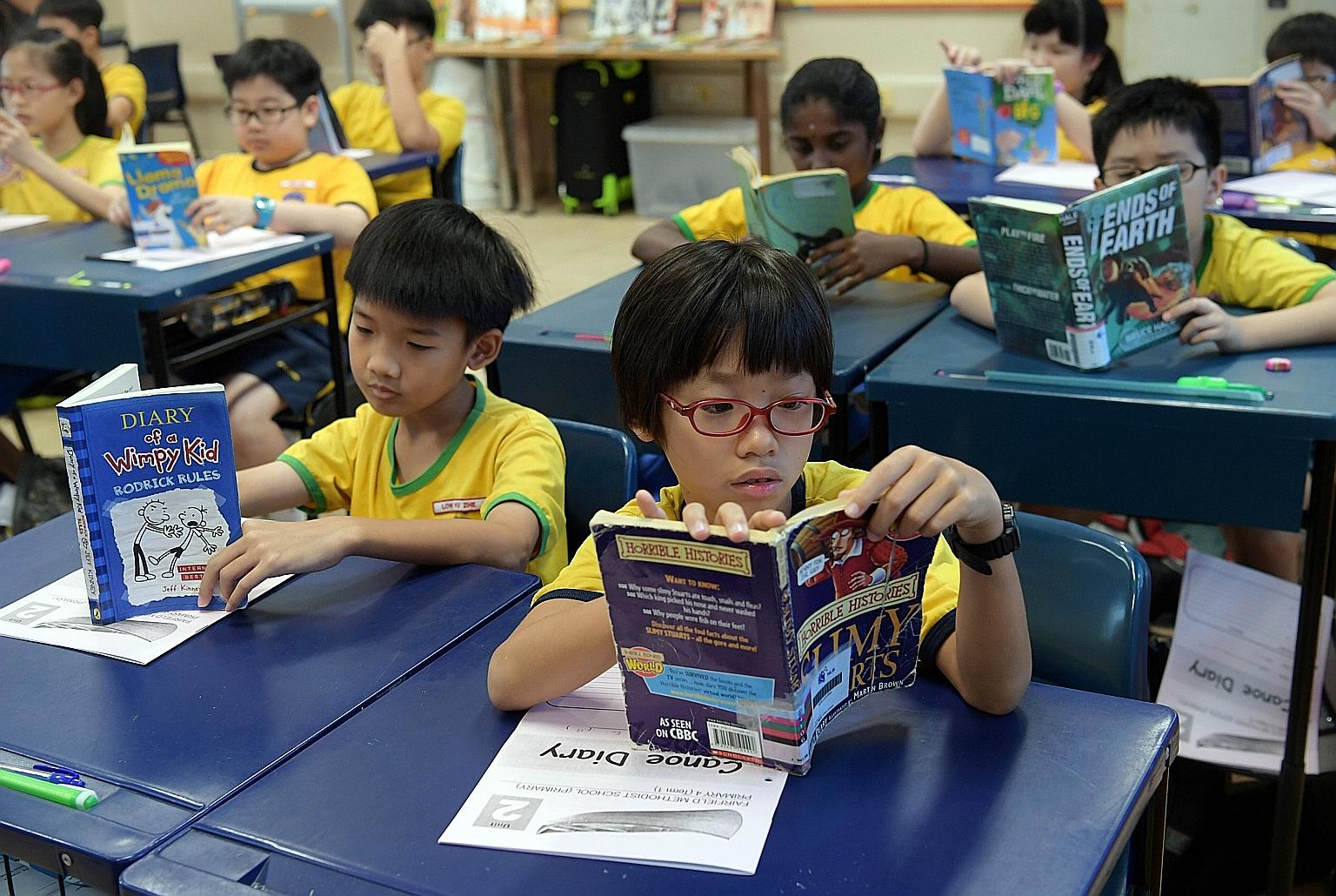 Primary 4 pupils at Fairfield Methodist Primary School reading books from the classroom library. The school pairs upper primary pupils with younger ones to help them with reading.