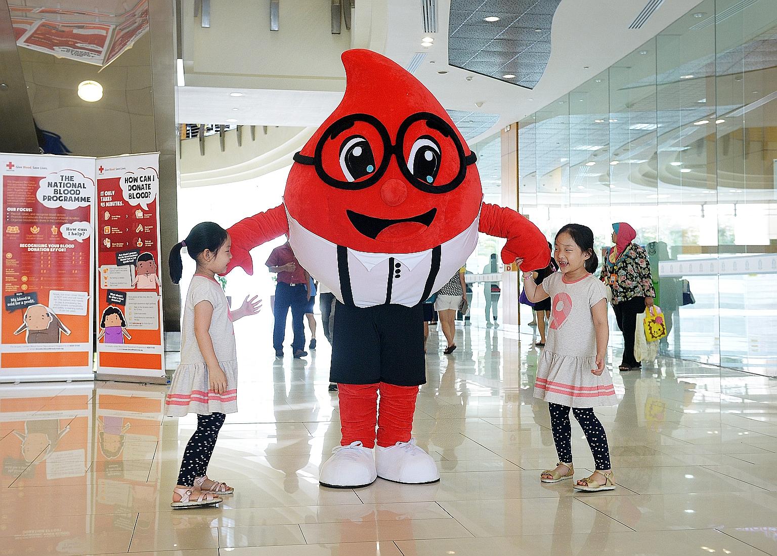 Seven-year-old twins Huang Sheng Yuan (far left) and Sheng Ting with journalist Toh Yong Chuan in his Blood Buddy mascot suit at the Woodlands Civic Centre last Saturday.