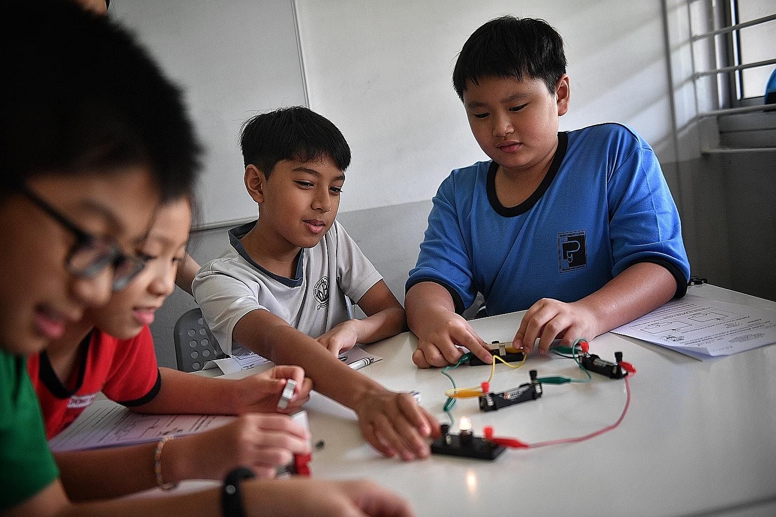 Children using a circuit diagram and magnets during class at EduFirst Learning Centre. Science specialist tutor Ephrem Chong conducting a hands-on activity with his pupils at Science Studios Learning Centre. Each two-hour lesson at the centre involve