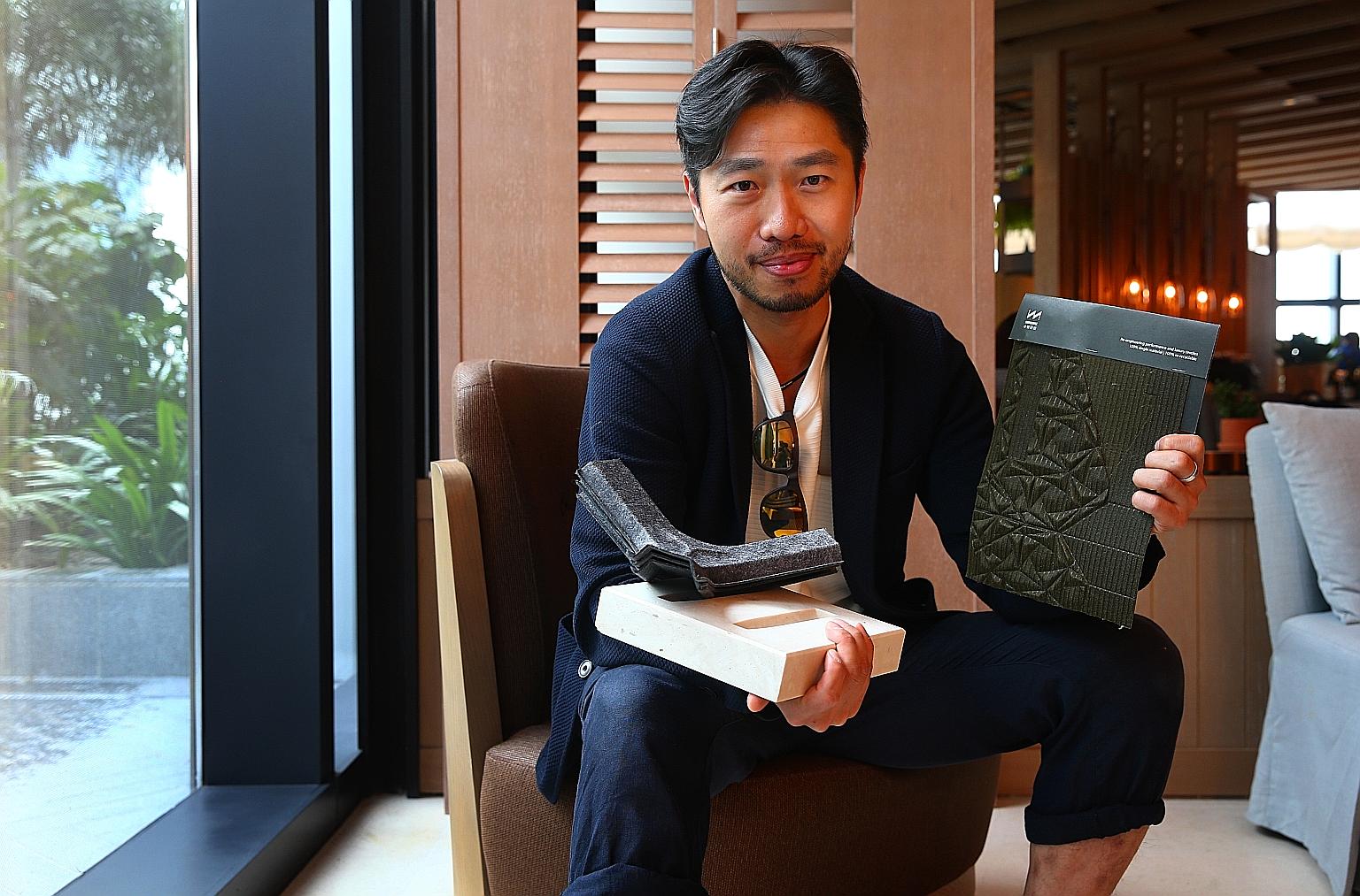 Mr Arthur Huang's upcycling company has created 1,200 new materials from trash. In his right arm is a concrete-like building material made from 2,000 cigarette butts. Sitting on it are air filters made from old clothes. The piece of fabric in his lef